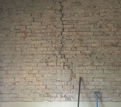 Extensive cracking in a brick wall with render removed
