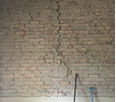 Extensive cracking in a brick wall with render removed